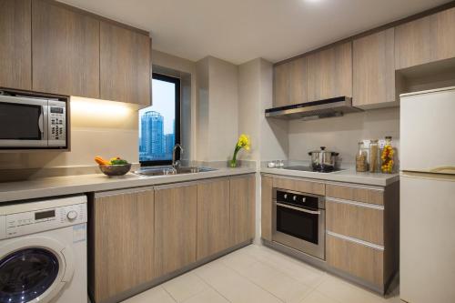 a kitchen with a washer and a sink and a microwave at Somerset Olympic Tower Tianjin in Tianjin