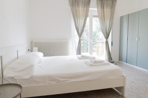 a white bedroom with a large bed and a window at Stadium Residence in Brescia
