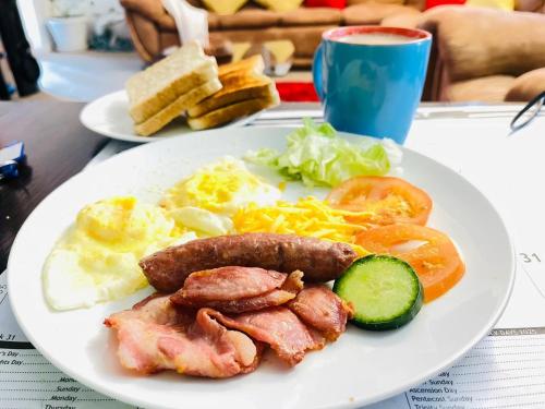 a plate of breakfast food with sausage and eggs at Mentor Guest house in Queenstown