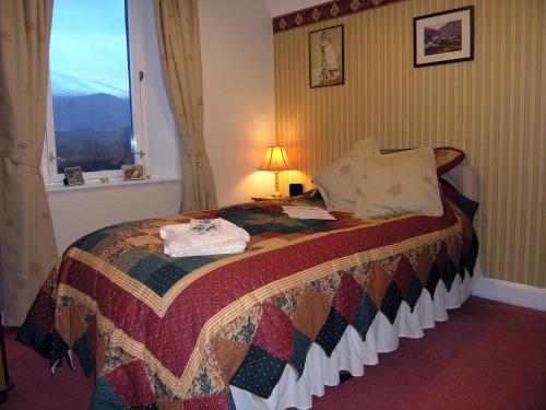 a bedroom with a bed with a quilt on it at Achnabobane Farmhouse in Spean Bridge