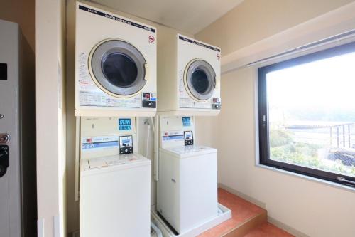a laundry room with two washing machines and a window at Quintessa Hotel Sasebo in Sasebo