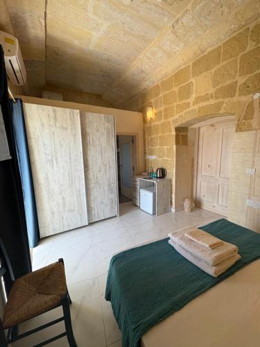 a bedroom with a bed in a room with a stone wall at Fiftyfour West Boutique Living in Għarb