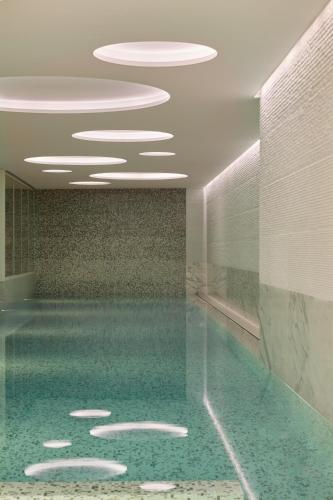 a swimming pool in a building with lights on the ceiling at The Woodward - Auberge Collection in Geneva