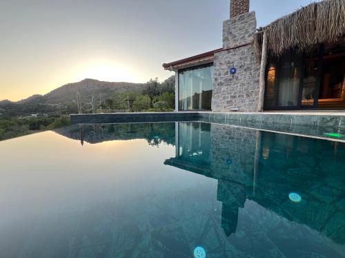 a villa with a swimming pool with the sun setting at Masarya house in Marmaris