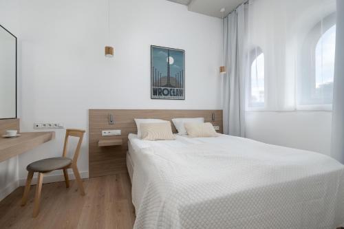 Un dormitorio con una cama, un escritorio y una silla. en PIEKARNIA Żywa Kultura Atmospheric Apartments in Wrocław by Noclegi Renters, en Wroclaw