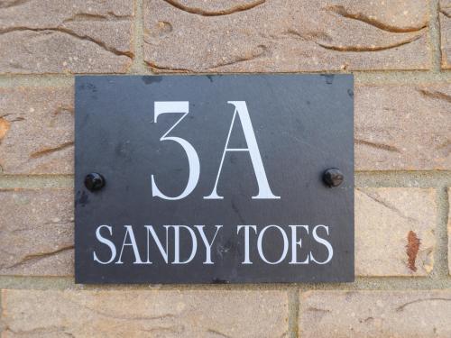 a sign on the side of a brick wall at Sandy Toes in Mablethorpe