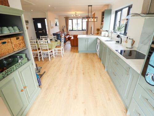 a kitchen with white cabinets and a wooden floor at Sandy Toes in Mablethorpe
