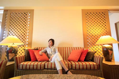 a woman sitting on a couch in a hotel room at Quintessa Hotel Sasebo in Sasebo