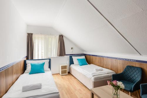 a room with two beds and a chair and a table at Hotel Solero in Siófok