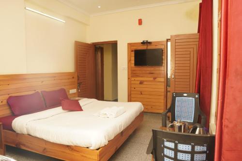 Un dormitorio con una cama y un televisor. en White Mountain By Pahadi Adda, en McLeod Ganj