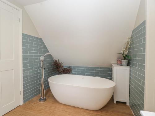 a bath tub in a bathroom with blue tiles at St Mary's House in Chipping Norton