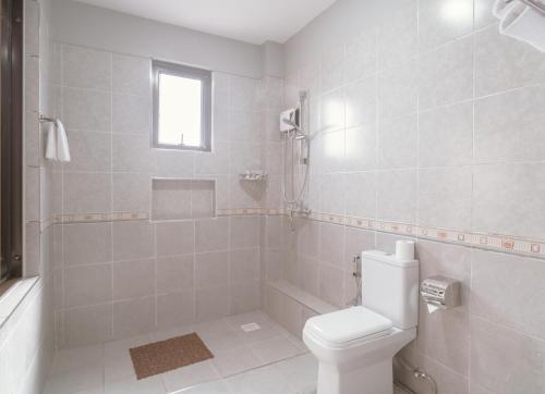 a white bathroom with a toilet and a shower at Skyview Opal Hotel in Ruiru