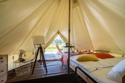 a tent with a bed and a tripod in it at Glamping Szelągówka, Sun & Snow in Sorkwity