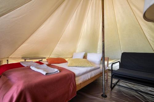 a bed and a chair in a tent at Glamping Szelągówka, Sun & Snow in Sorkwity