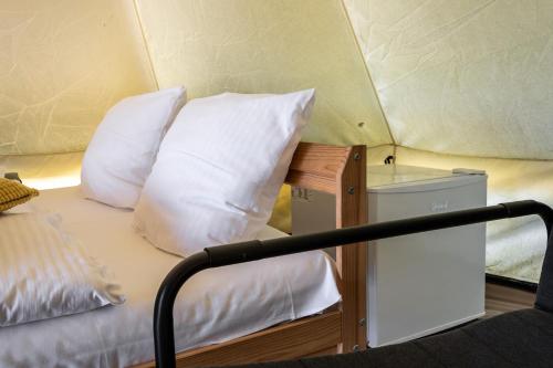 a bed with white pillows in a room at Glamping Szelągówka, Sun & Snow in Sorkwity