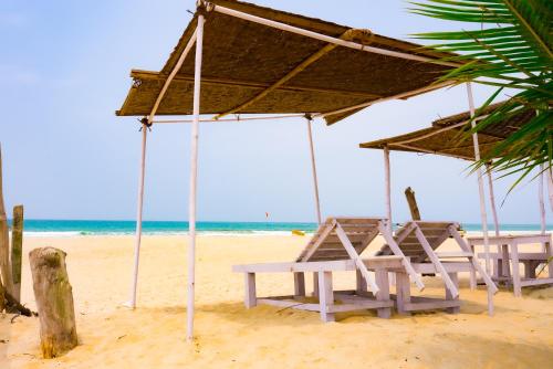 a beach with two chairs and an umbrella on the sand at Sea Breeze Goa in Talaulim