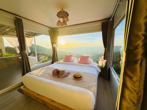 a bed in a room with a large window at ชิวชิวแคมป์ ภูชี้ฟ้า in Ban Huai Han