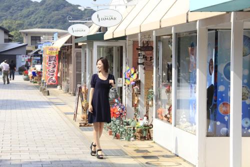 a woman walking down a street in front of shops at Quintessa Hotel Sasebo in Sasebo