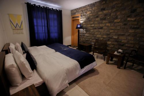 a bedroom with a large bed and a brick wall at Roomy Mountain Top Resort, Batakundi in Battakundi