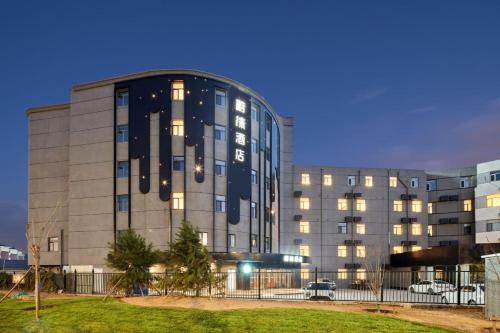 ein großes Gebäude mit eingeschalteten Lichtern davor in der Unterkunft VYLUK Hotel Beijing Universal Studios-蔚徕酒店 北京环球影城店 in Peking