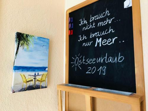 a chalkboard with a table and chairs on a beach at Gericke Bungalow GM 69303 in Graal
