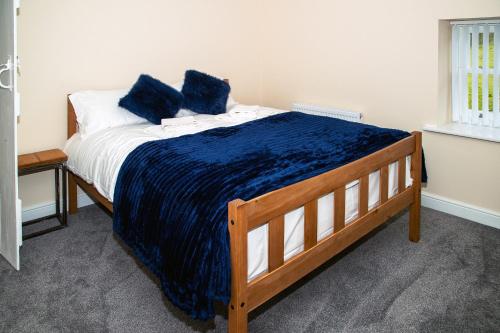 Rose Cottage, Kepwick Village with Hot Tub - Rural Location في Kepwick: سرير عليه وسائد زرقاء في غرفة
