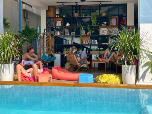 a group of people sitting next to a swimming pool at THE PLACE Hostel Siem Reap Angkor in Siem Reap