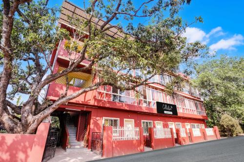 a red building with a tree in front of it at Collection O Anjuna 5 Mins Walk From Anjuna in Anjuna
