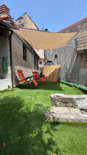 two chairs in a yard with a large umbrella at Bella casa nel cuore del Cilento in Montano Antilia