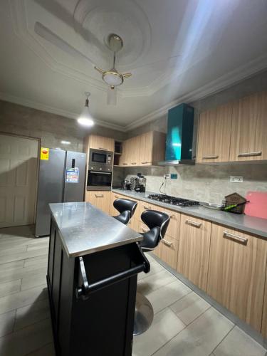 a kitchen with a black refrigerator and wooden cabinets at Serene 2 bedroom fully furnished house in Haatso