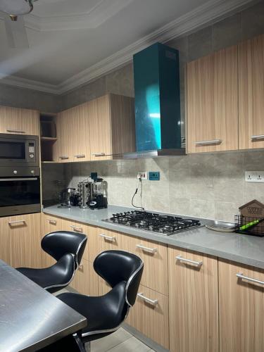a kitchen with a stove and some black chairs at Serene 2 bedroom fully furnished house in Haatso