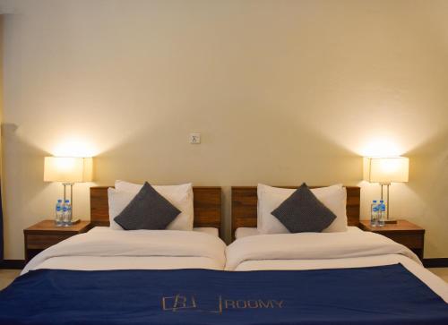 a bedroom with two beds with pillows and two lamps at Roomy Mountain Top Resort, Batakundi in Battakundi