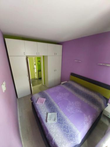 a room with a purple bed and white cabinets at Apartmani Pelivan in Soko Banja
