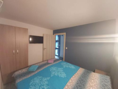 a bedroom with a bed with a blue blanket at Apartmani Pelivan in Soko Banja