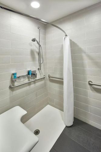 a bathroom with a shower with a white shower curtain at Aloft Raleigh in Raleigh