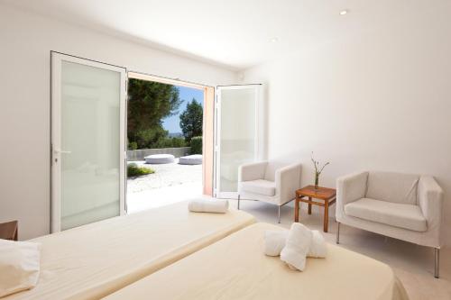 une chambre blanche avec un lit et deux chaises dans l'établissement Stunning Seaside Oasis in Ibiza, 1049, à Port des Torrent