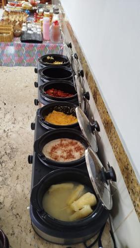 a row of pans of food on a stove at Villa Mar Boa Viagem in Recife