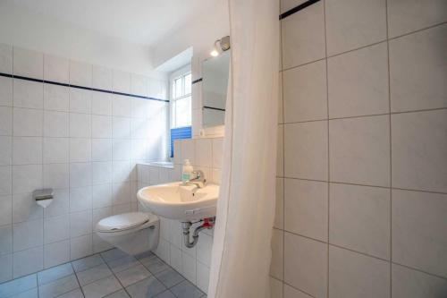 a white bathroom with a sink and a toilet at Wohnung 5 ID 389 in Süderhöft
