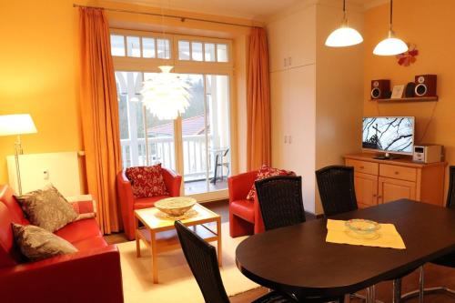 a living room with a table and red chairs at Dünenschloss - 02-29 in Kühlungsborn