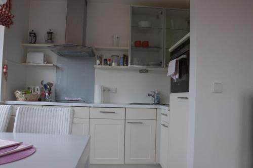 a kitchen with white cabinets and a white refrigerator at Schönes Wohnen am Nordseestrand in Wyk auf Föhr