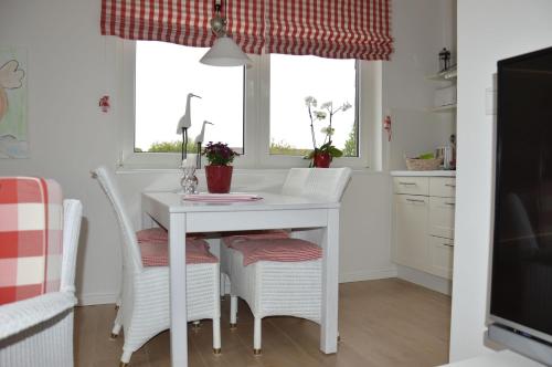 a kitchen with a white table and white chairs at Schönes Wohnen am Nordseestrand in Wyk auf Föhr