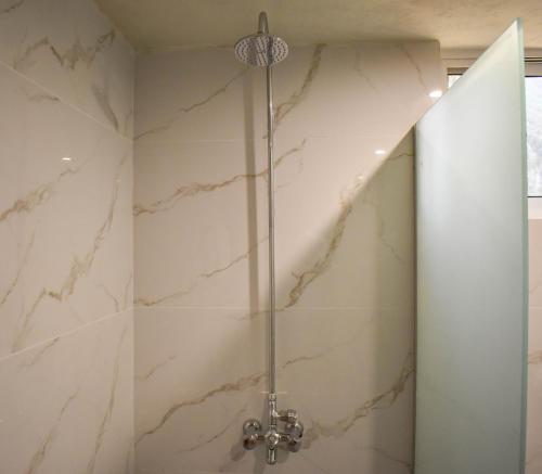 a shower in a bathroom with white marble at Roomy Mountain Top Resort, Batakundi in Battakundi