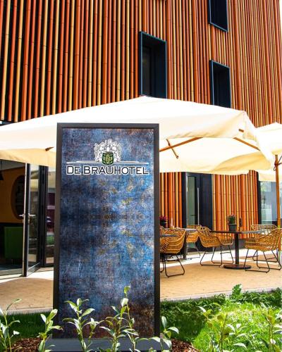 a sign under an umbrella in front of a building at De Brauhotel - Hôtel de la Brasserie Nationale in Bascharage
