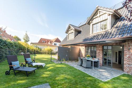 un patio trasero con 2 sillas y una mesa en el césped en Wildrose, en Zingst