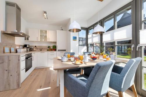 cocina con mesa de madera y sillas azules en Wildrose, en Zingst