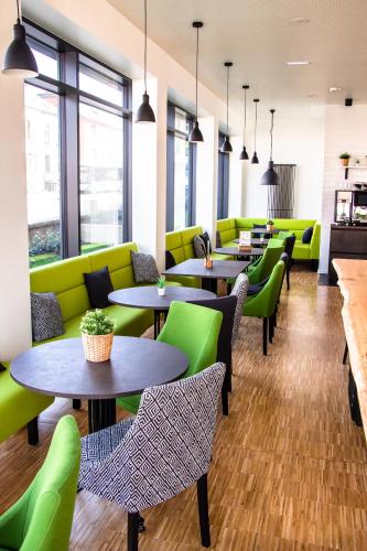 a restaurant with tables and green chairs at De Brauhotel - Hôtel de la Brasserie Nationale in Bascharage