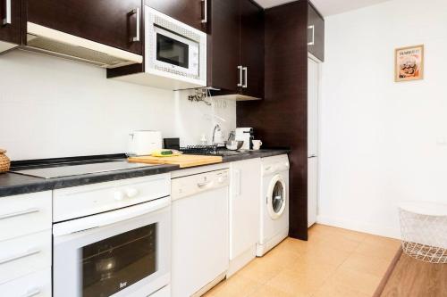 a kitchen with white cabinets and a washer and dryer at Casa Cosmos Arcade WiFi 4 Huéspedes in Zaragoza