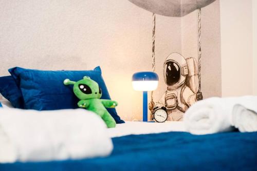 a green teddy bear sitting on top of a bed at Casa Cosmos Arcade WiFi 4 Huéspedes in Zaragoza