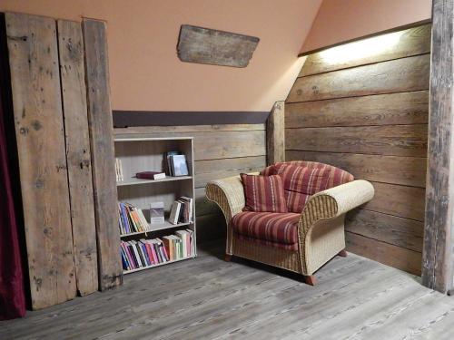 a living room with a chair and a book shelf at Ferienwohnungen Bekperle in Bekdorf