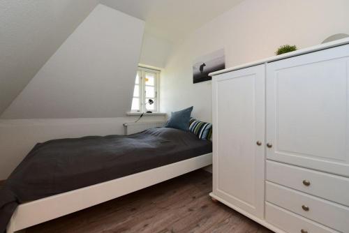 a white bedroom with a bed and a white cabinet at Haus Kliffkante 1 Goting in Goting